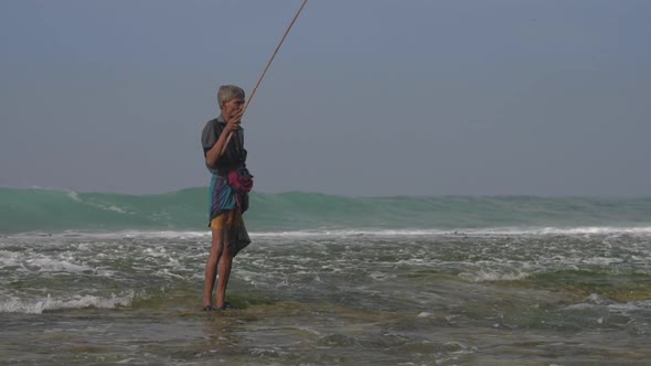 Fisherman Stands in Foaming Ocean Water Under Cloudy Sky