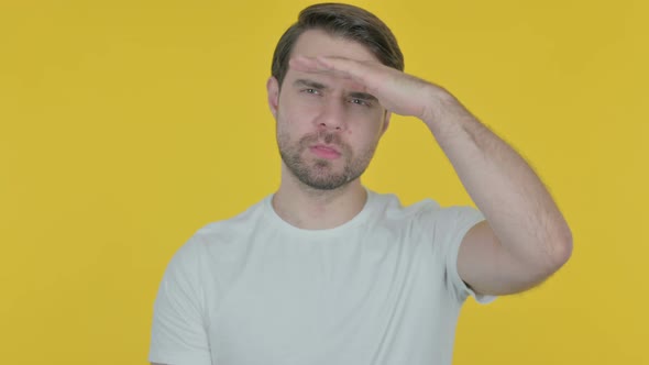 Young Man Looking Around, Searching on Yellow Background