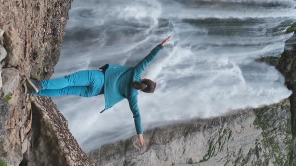 Woman Standing By Waterfall with Hands Raised