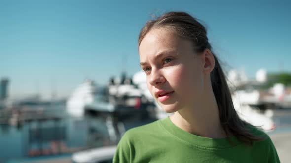 Handsome blonde woman wearing green t-shirt looking at view and at the camera on the seafront