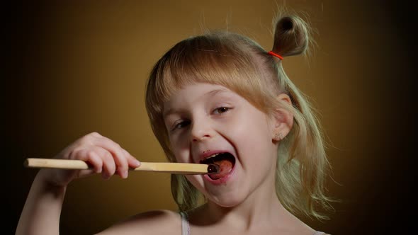 Joyful Smiling Child Kid Girl with Dirty Face From Melted Chocolate on Dark Background in Studio