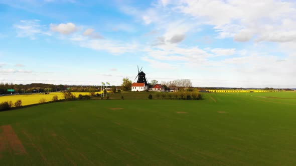 Drone approaching windmill flying over green field. Sweden springtime