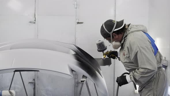 Male Specialist Is Colouring Metal Car Detail in Black, Working in Paint Chamber