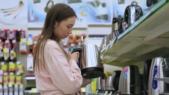 Young Woman is Buying an Electric Kettle in Shopping Mall