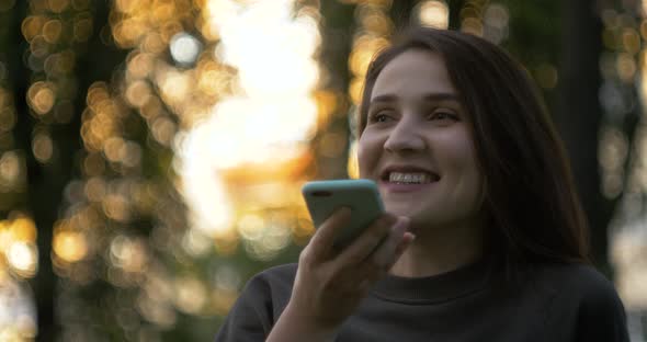 Happy Girl Using a Smart Phone Voice Recognition Audio Message Function on Line Walking on a Street