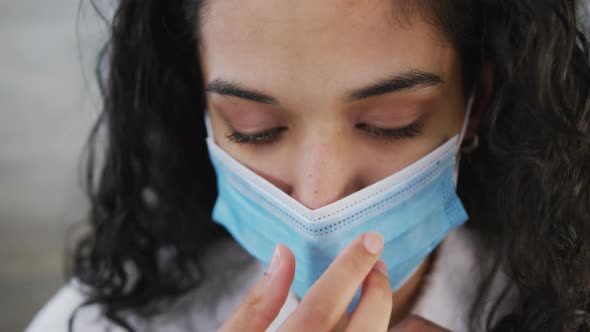 Portrait close up of mixed race woman with long dark hair putting face mask on in slow motion