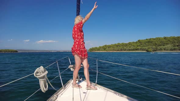 Woman Waving Hello Greeting on Bow of a Sailboat