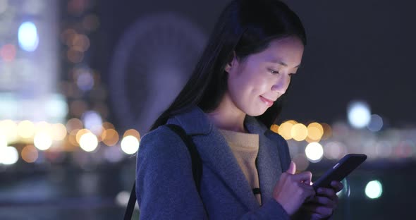 Asian Woman use of cellphone in city at night