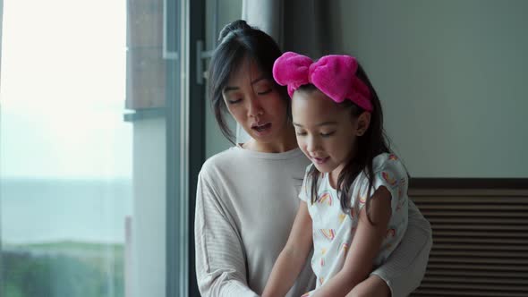 Positive Asian daughter with mom hugging stroking dog