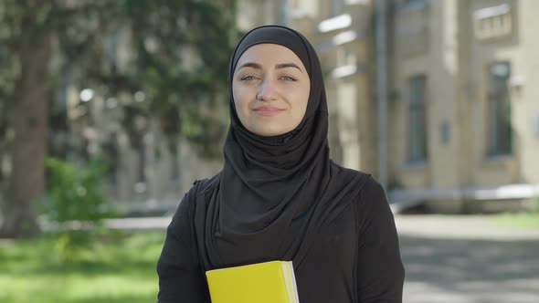 Young Proud Muslim Woman in Traditional Black Hijab Posing on Sunny Day at University Yard. Portrait