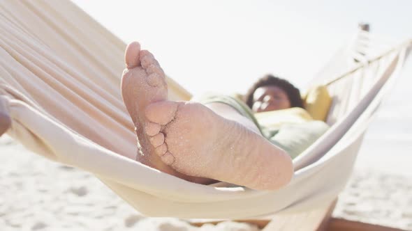 Happy african american woman lying in hammock on sunny beach