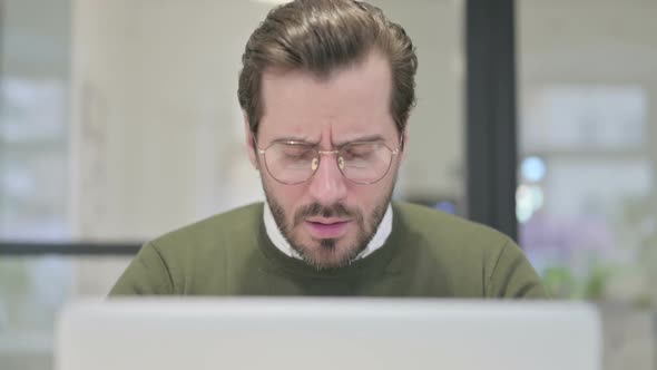 Close Up of Young Businessman Coughing While Using Laptop