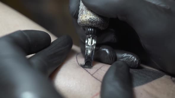 Skilled Tattoo Salon Worker in Gloves Applies Black Ink