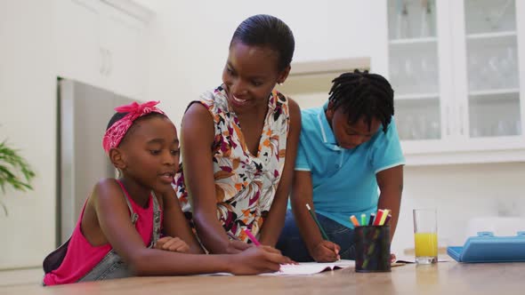African american mother helping her daughter and son with homework at home