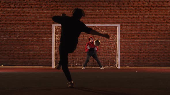 Two Young Men Playing Football on the Playground at Night