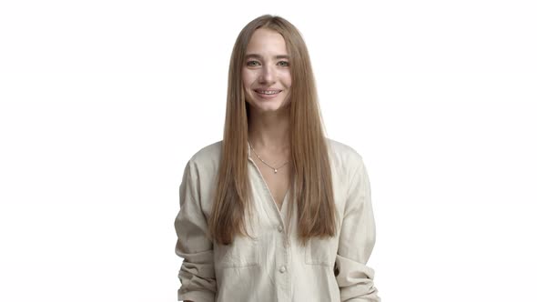 Young Pretty Blond Woman with Braces Wearing Beige Blouse Showing Okay Sign Winking and Saying