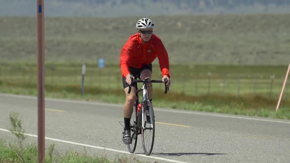 A man road biking on a scenic road.