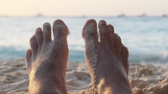 POV Feet of Young Man Lying on Sandy Beach By the Ocean During Sunset Zanzibar