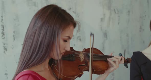 View of Admiring Female Musician in Red Dress Playing the Violin at Camera