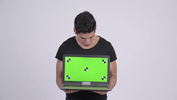 Happy Young Multi-ethnic Man Looking Surprised While Showing Laptop