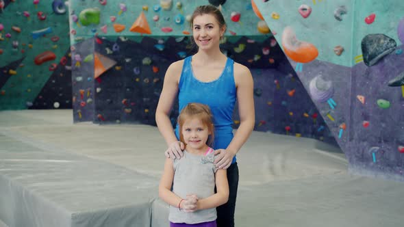 Portrait of Happy Young Woman and Little Girl in Sportswear Standing in Indoor Climbing Gym