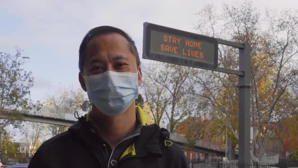 A sign reads 'Stay Home, Save Lives' behind a man wearing a mask during the coronavirus outbreak.