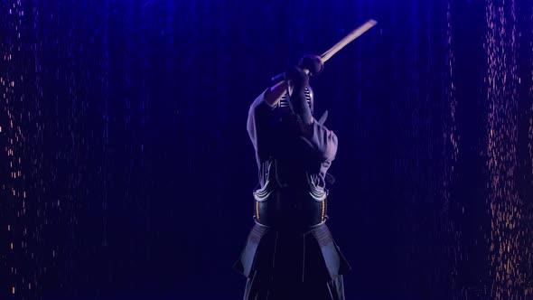 Portrait of a Japanese Kendo Fighter Lowering His Shinai Towards the Camera. Shot in a Dark Studio