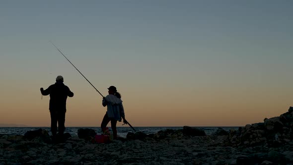 Two People Fishermen a Man and a Woman Fishing at Sunset
