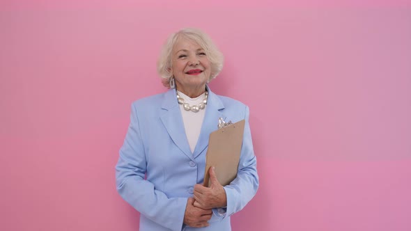 Portrait of a Stylish Elderly Woman in an Elegant Business Suit Holding a Tablet and Smiling at the