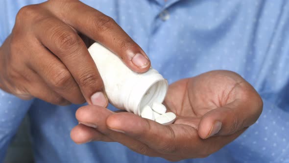 Close Up of Man Hand Taking Pills Isolated in Black 