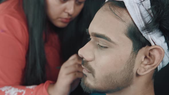 Close up of man's face and make up artist fixing his beard with make up brush