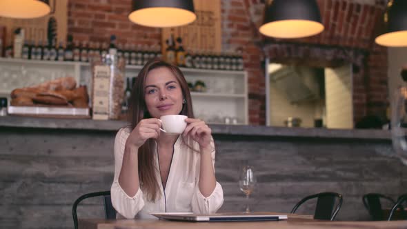 Beautiful young girl drinks coffee