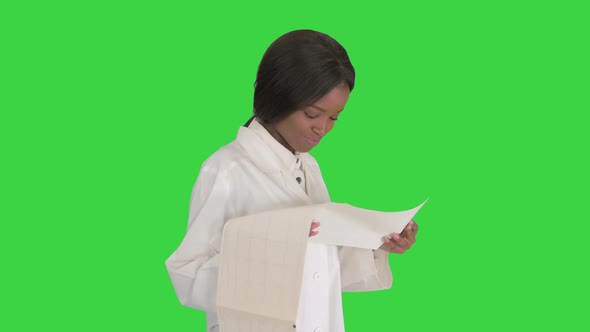 Smiling African American Female Doctor Reading Cardiogram on a Green Screen, Chroma Key.