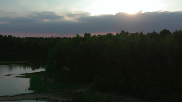 Countryside Dramatic and Colorful Sunset Flight Over a Forest Lake Aerial Shot on a Drone