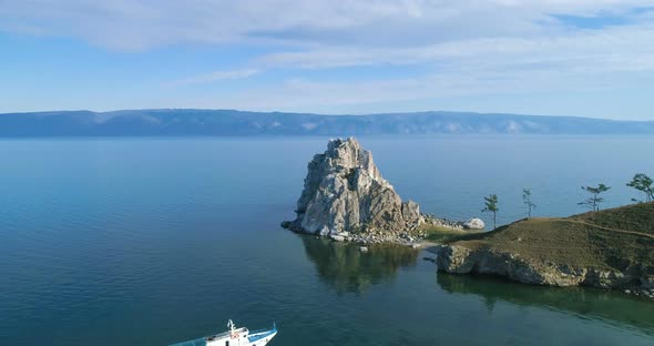 View of the Calm Bay of Lake Baikal. A Rock Shamanka and a White Ship at Anchor