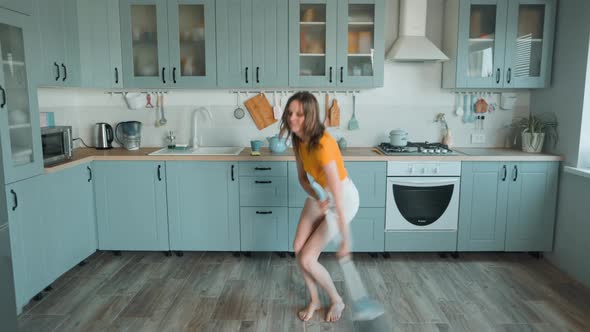 A Beautiful Woman in White Shorts is Relaxing at Home Dancing in the Kitchen