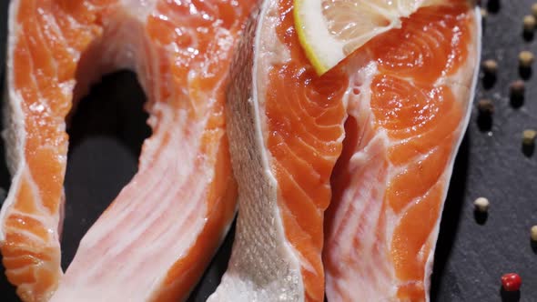 Fresh Piece of Salmon Placed on Cutting Board on Kitchen Table with Spices Lemon