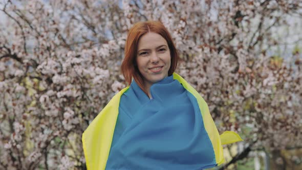 Smiling Feemale with Ukrainian Flag in Blossoming Park