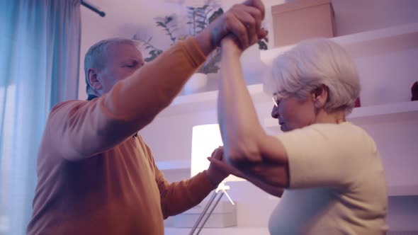 Happy Elderly Couple Dancing with Disco Lights in Hotel Room