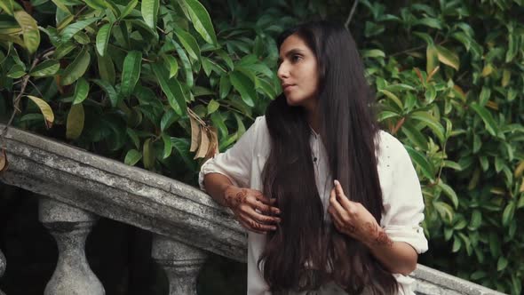 Alone Arabian Woman Is Standing in a Tropical Garden and Touching Her Long Hair