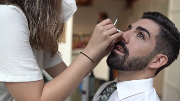 Make-up artist wearing protective mask, applying make-up for wedding