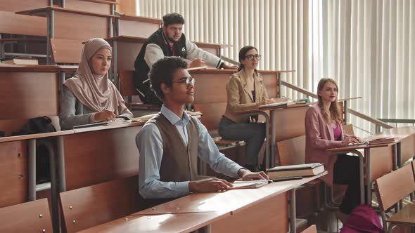 Multi-Ethnic University Students with Raised Hands during Seminar