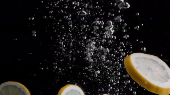 Lemon Slices Falling into Water Super Slowmotion, Black Background, lots of Air Bubbles, 4k240fps