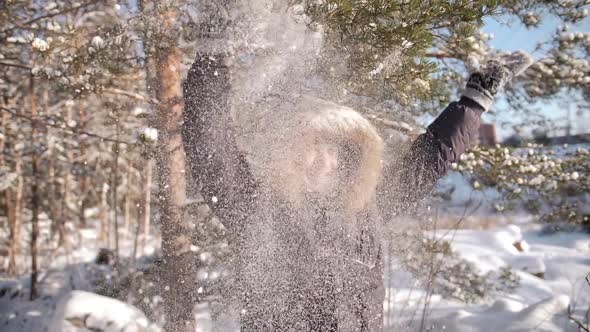 A Cheerful Guy Shakes a Snowy Tree Branch on His Head