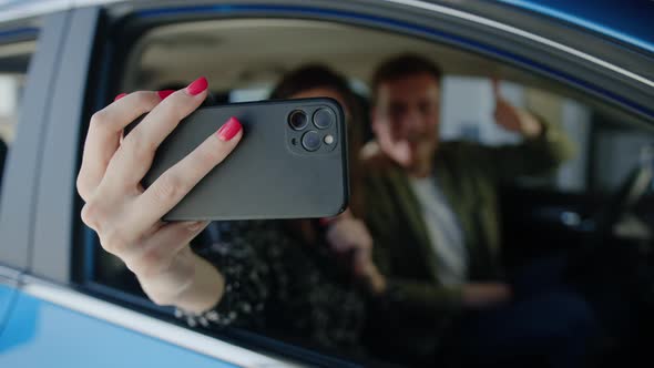 A Young Couple Takes a Selfie in a New Car They Bought at a Dealership