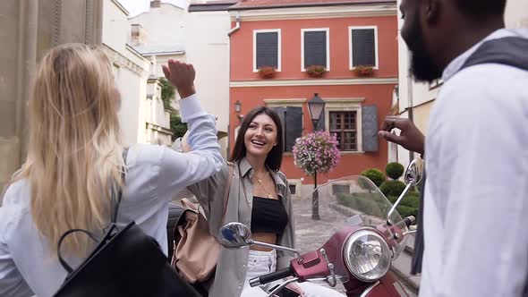 Cheerful Woman Sitting on the Scooter and Giving High Five to Her Mixed Races Friends