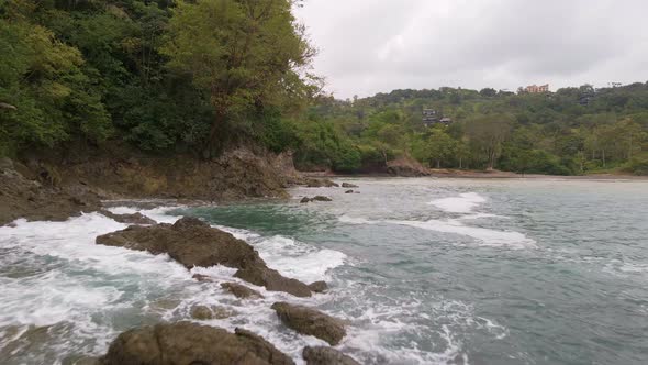 backwards drone flight over the ocean and the white foaming waves hitting the rocky coastline