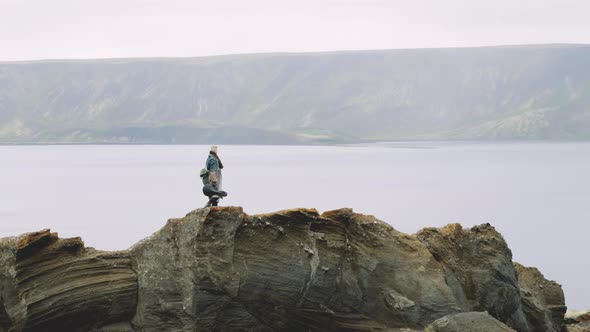 Man With Guitar Case Standing On Rock In Icelandic Landscape