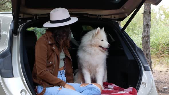 A woman is playing in nature with her four-legged friend, the dog Samoyed.