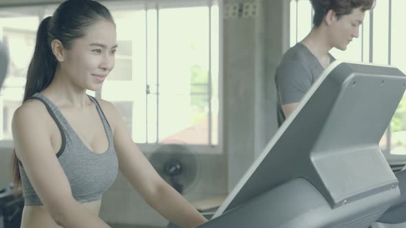 Asian young man and woman doing cardio exercise training with running on treadmill in sport gym.